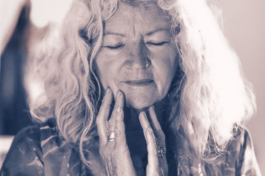 Open Inward Portrait of a beautiful mature woman, hands near jaw, eyes closed, meditating, connected, side lighting.